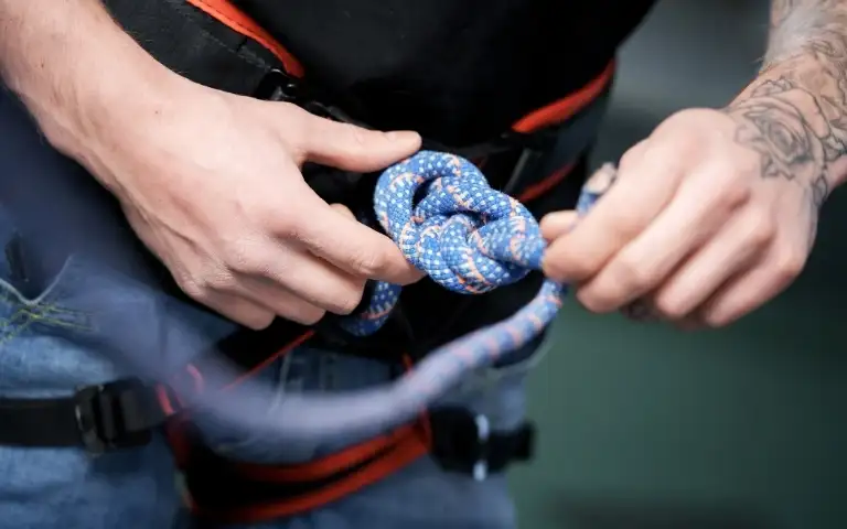 Mężczyzna poprawiający linę przywiązaną do uprzęży