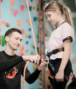 Mężczyzna przygotowuje dziewczynkę do wspinaczki